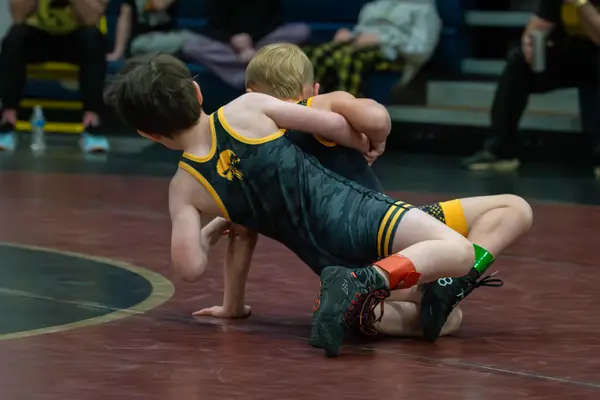 A Rangers wrestler drives an opponent across a maroon mat