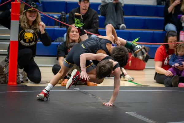 A wrestler is thrown near the mat edge as Rangers fans cheer