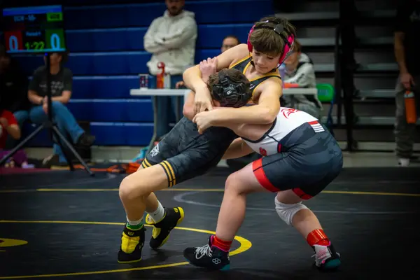 A young Rangers wrestler in pink headgear ties up with an opponent
