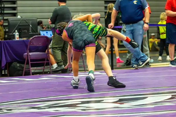 A Rangers wrestler in pink-trimmed gear works against an opponent in green camo