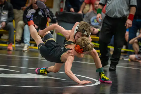 Two young wrestlers scramble as one is lifted off the mat