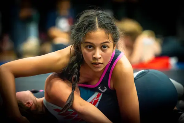 A Rangers wrestler looks up from the mat while controlling an opponent