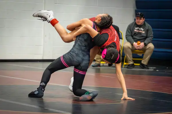 A Rangers wrestler throws an opponent in red near the mat edge