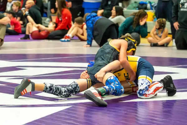 Two young wrestlers scramble on a purple and white mat