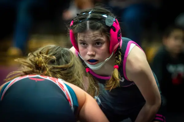 A Rangers wrestler in pink headgear stares down an opponent