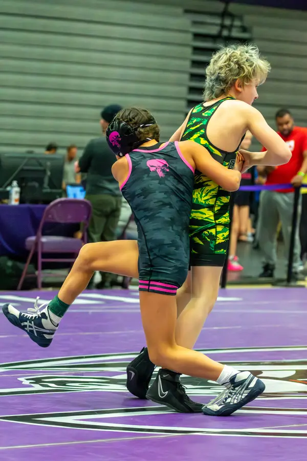 A Rangers wrestler drives into an opponent in a green camo singlet