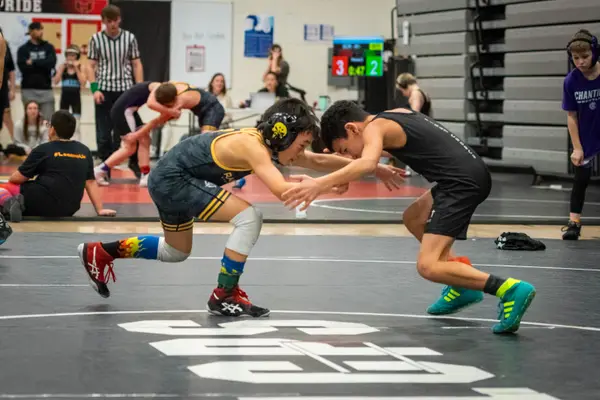 Two young wrestlers circle each other with hands out on a black mat