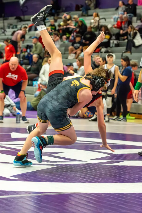 A Rangers wrestler is upended mid-throw in front of a packed gym