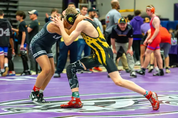 A Rangers wrestler ties up with an opponent at a crowded tournament