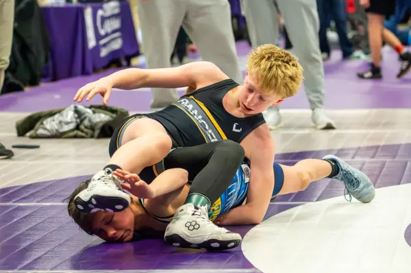 A Rangers wrestler works to turn an opponent on a purple mat