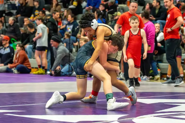 A young Rangers wrestler wraps up an opponent on a purple mat