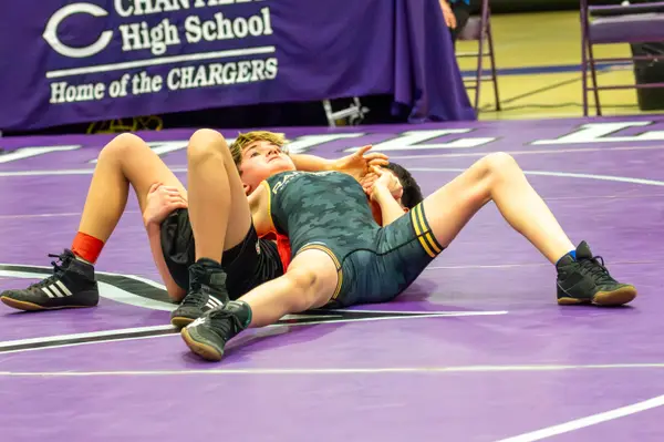 A Rangers wrestler works for a pin on a purple mat