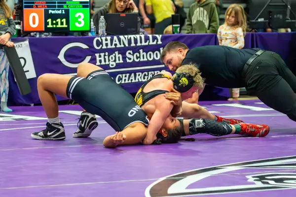 A Rangers wrestler controls an opponent as the referee gets low for a view