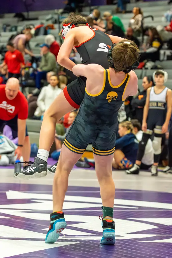 A Rangers wrestler lifts an opponent's leg in front of the stands