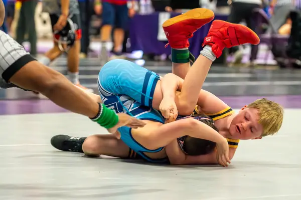 A Rangers wrestler pins an opponent in light blue as the referee slaps the mat