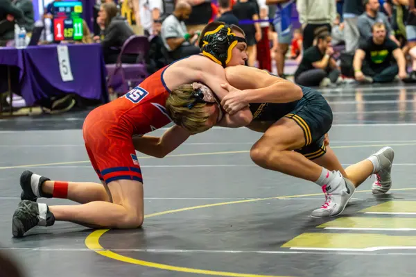 A Rangers wrestler ties up with an opponent in a red singlet