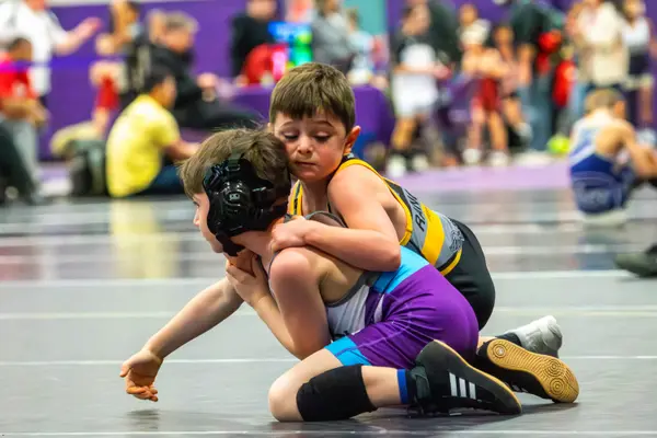 A young Rangers wrestler wraps up an opponent in a purple singlet