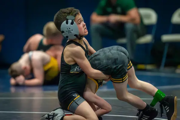 A young Rangers wrestler grits their teeth while driving into an opponent