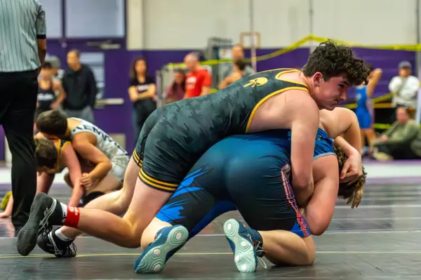 A Rangers wrestler rides an opponent in a blue singlet