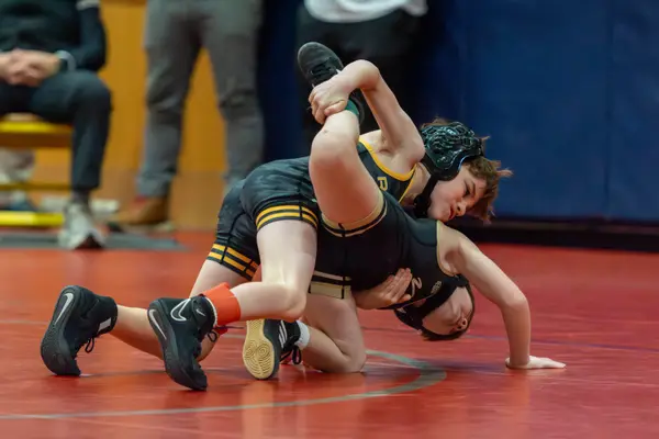 A young Rangers wrestler controls an opponent on a red mat